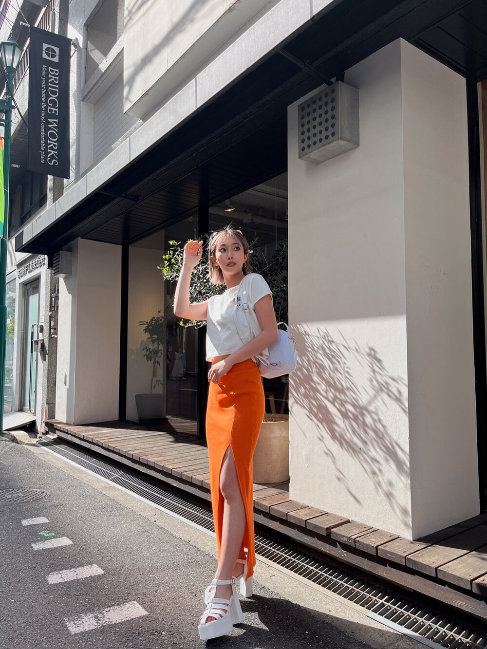ホワイト系のTシャツ/カットソー、オレンジ系のスカートを着用したレディースの春コーディネートの2枚目の写真