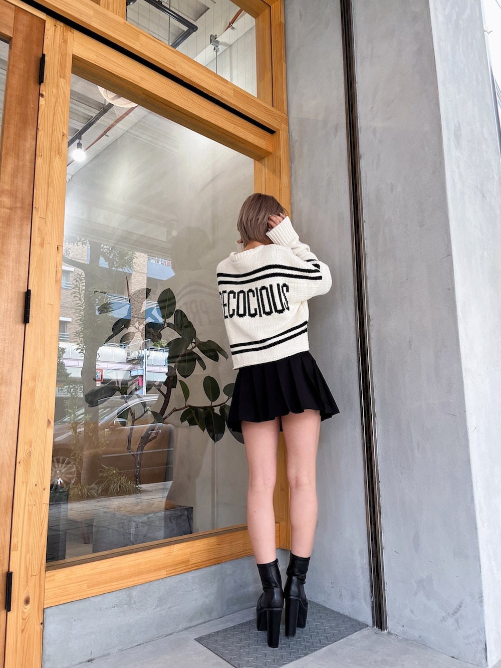 ホワイト系のニット/セーター、ブラック系のスカート、ブラック系のブーツを着用したレディースの冬コーディネートの5枚目の写真