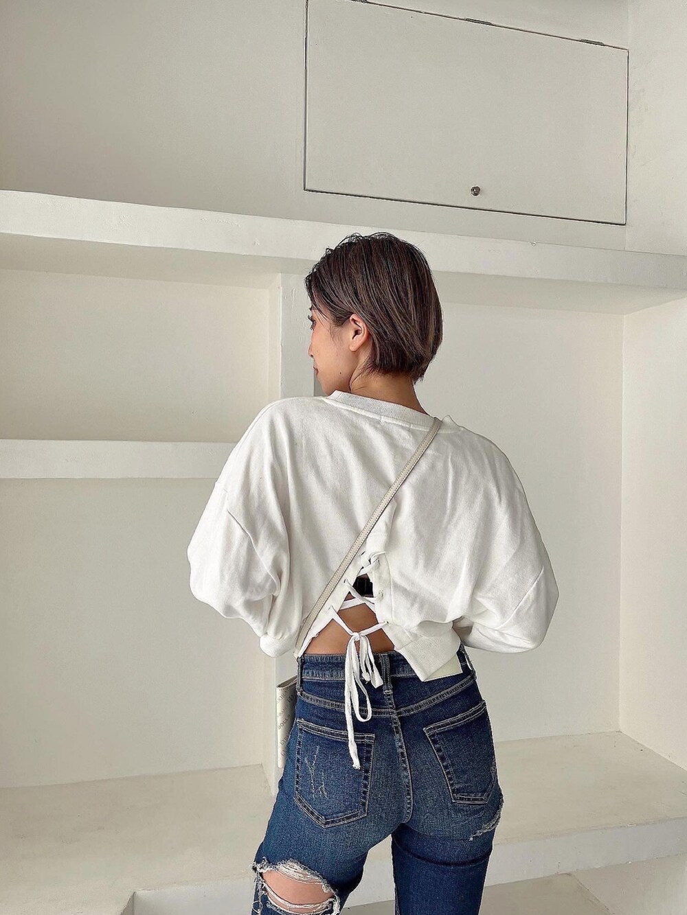 ホワイト系のスウェット、ブルー系のデニムパンツ、ブラック系のパンプスを着用したレディースの冬コーディネートの3枚目の写真