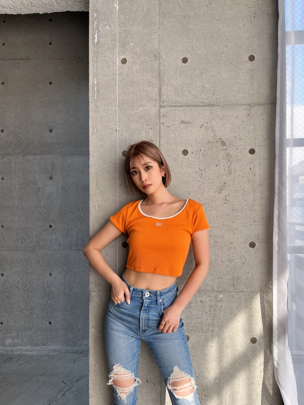 オレンジ系のTシャツ/カットソーを着用したレディースの春コーディネートの2枚目の写真