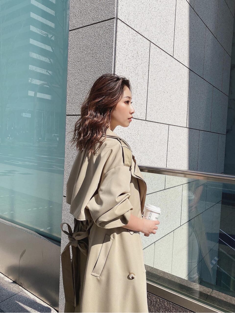 ベージュ系のトレンチコート、ホワイト系のデニムパンツ、ホワイト系のニット/セーターを着用したレディースの春コーディネートの2枚目の写真