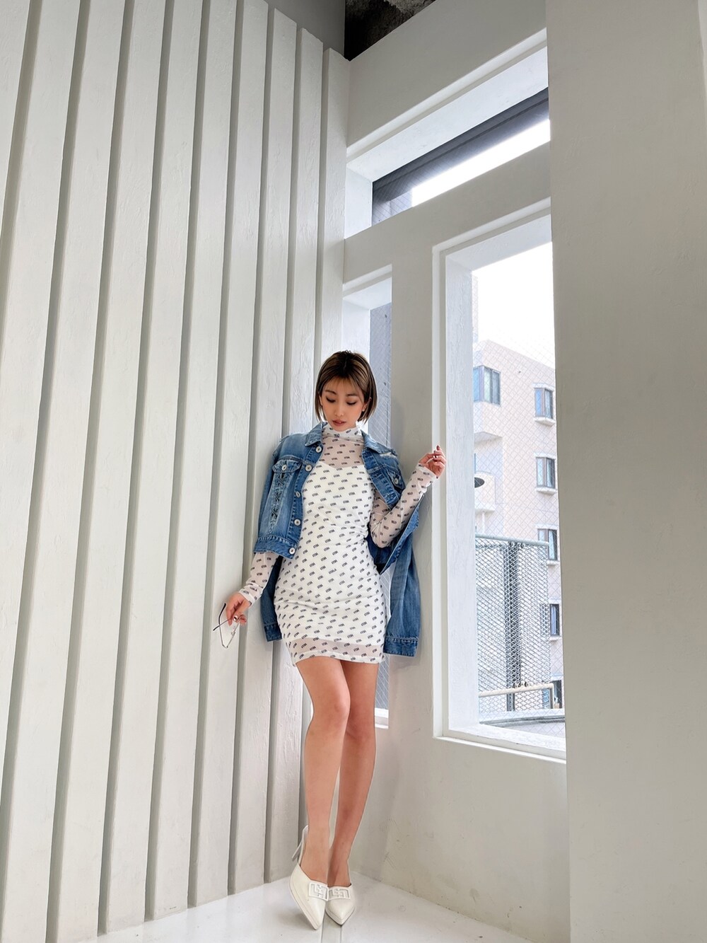 ブルー系のデニムジャケット、ホワイト系のワンピース、ホワイト系のパンプスを着用したレディースの春コーディネートの2枚目の写真