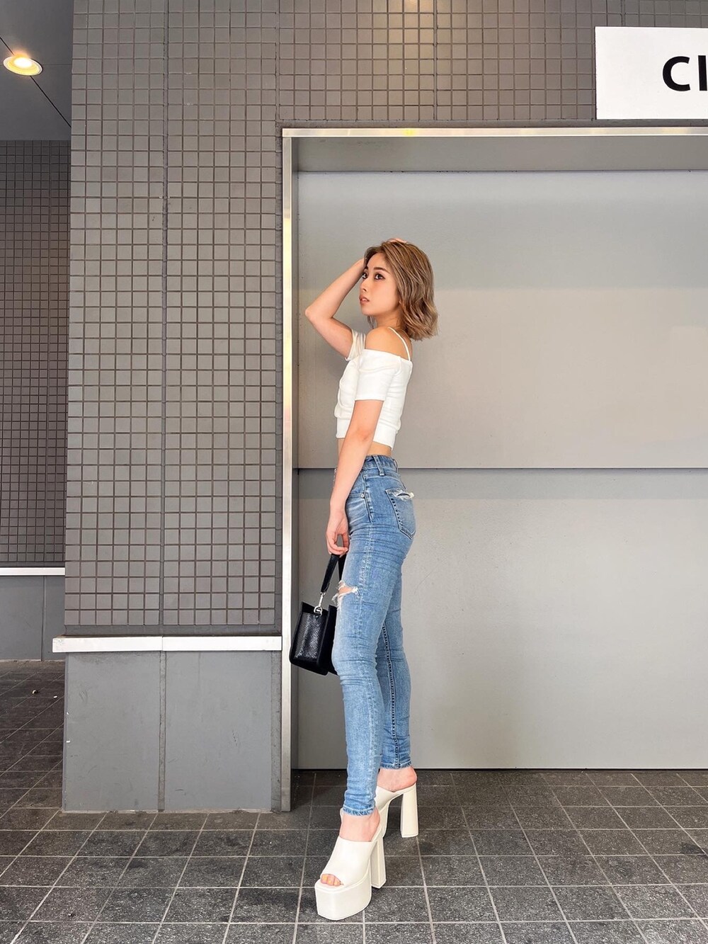 ブルー系のデニムパンツ、ホワイト系のTシャツ/カットソー、ブラック系のサンダルを着用したレディースの夏コーディネートの3枚目の写真