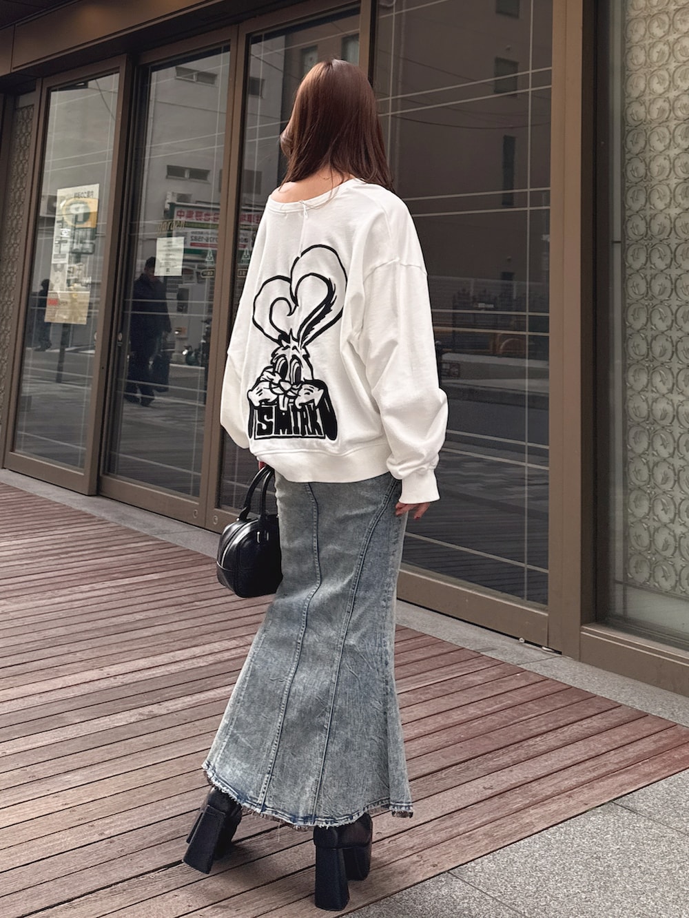 ホワイト系のスウェット、ブルー系のデニムスカートを着用したレディースの冬コーディネートの2枚目の写真