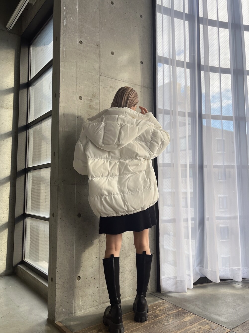 ブラック系のワンピース、ブラック系のブーツ、ホワイト系のダウンジャケット/コートを着用したレディースの冬コーディネートの2枚目の写真