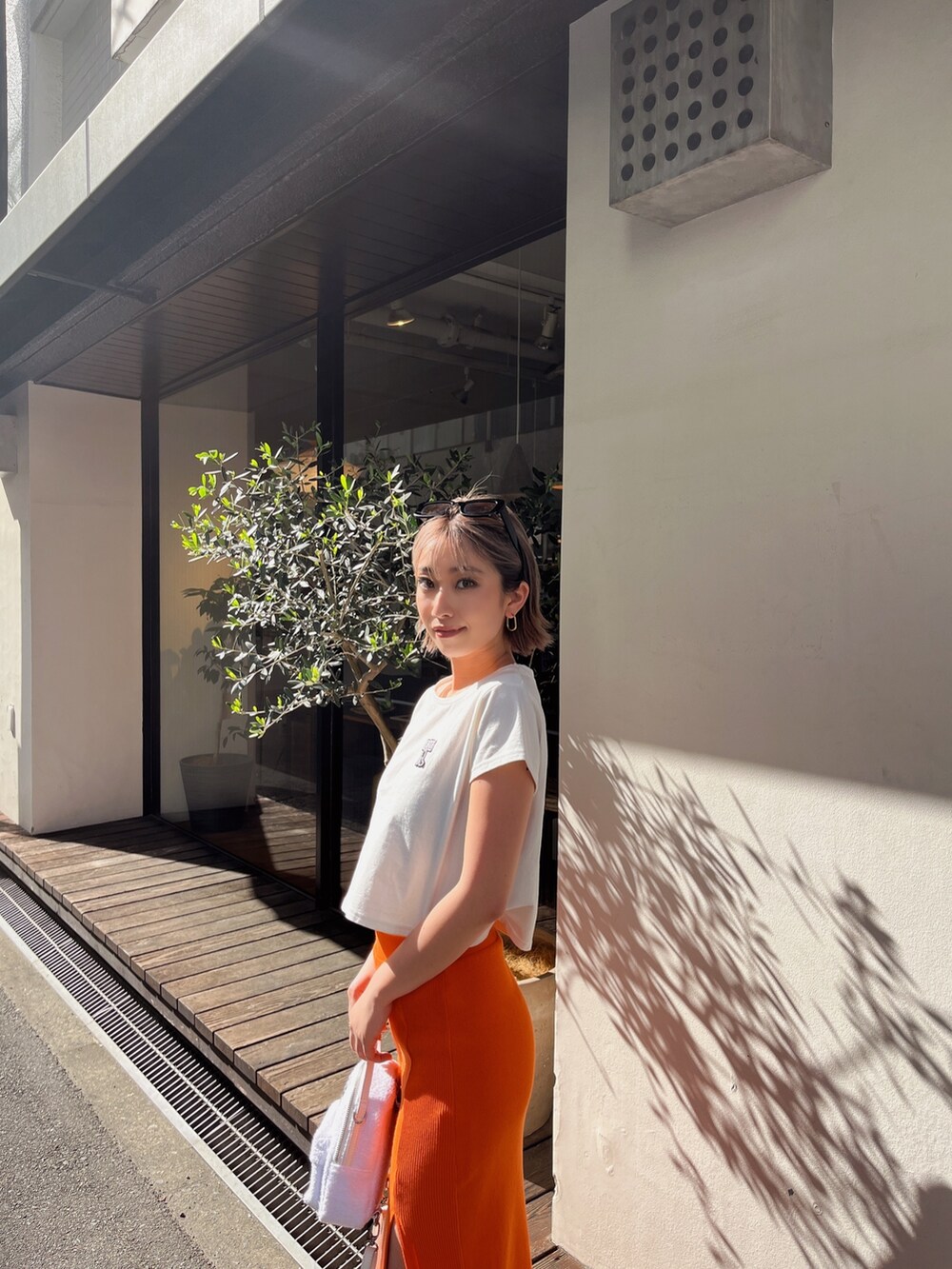 ホワイト系のTシャツ/カットソー、オレンジ系のスカートを着用したレディースの春コーディネートの6枚目の写真