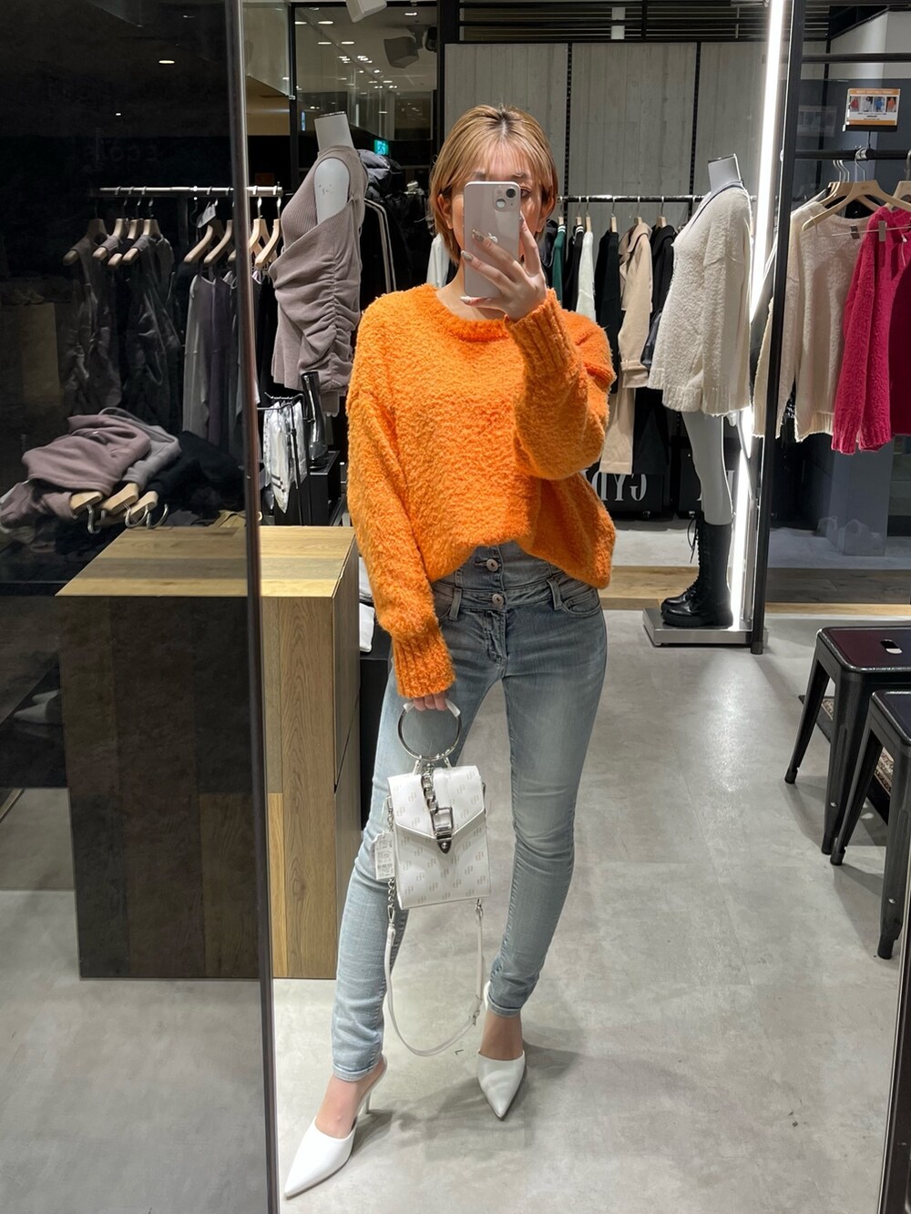 ブラック系のショルダーバッグ、ブラック系のブーツ、ホワイト系のニット/セーターを着用したレディースの冬コーディネートの3枚目の写真