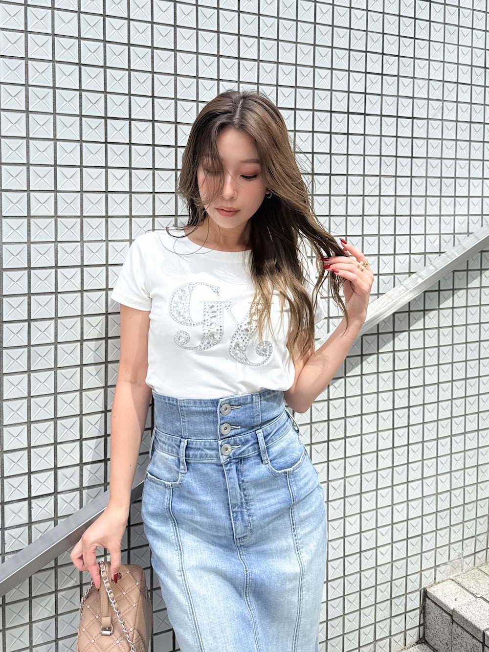 ブルー系のデニムスカート、ホワイト系のTシャツ/カットソー、ホワイト系のサンダルを着用したレディースの秋コーディネートの3枚目の写真