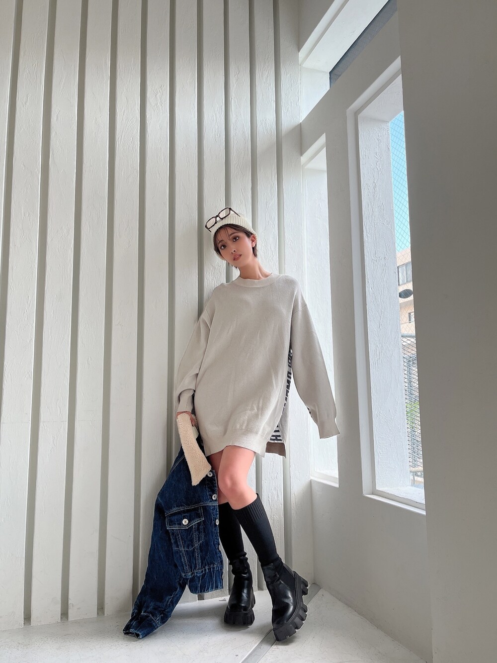 ホワイト系のニット/セーター、ブルー系のデニムジャケット、ブラック系のブーツを着用したレディースの秋コーディネートの2枚目の写真