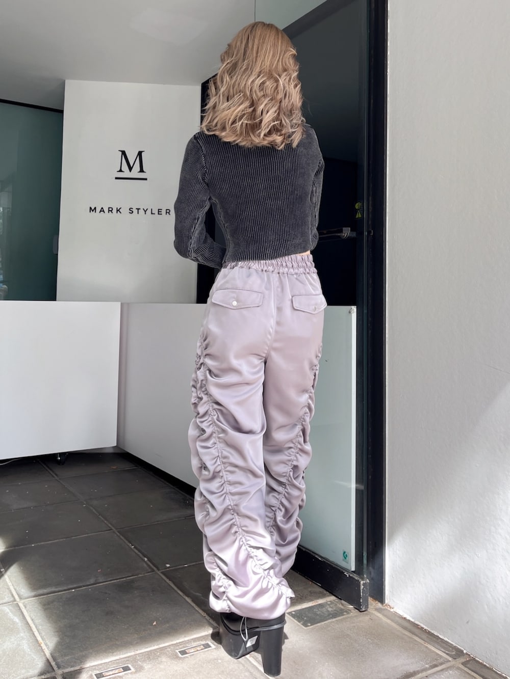 グレー系のその他パンツ、ブラック系のニット/セーター、ブラック系のブーツを着用したレディースの秋コーディネートの6枚目の写真