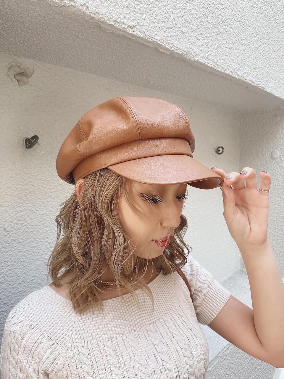 ホワイト系のニット/セーター、ホワイト系のスカート、ブラウン系のショルダーバッグを着用したレディースの夏コーディネートの2枚目の写真