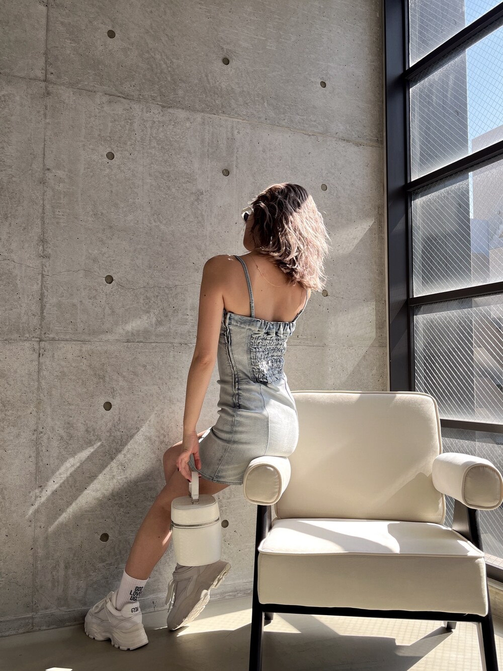 ブルー系のワンピース、ブラック系のハンドバッグ、ホワイト系のサングラスを着用したレディースの春コーディネートの5枚目の写真