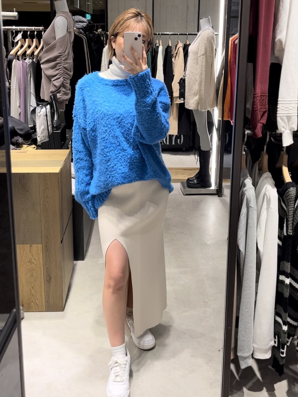 ブラック系のショルダーバッグ、ブラック系のブーツ、ホワイト系のニット/セーターを着用したレディースの冬コーディネートの2枚目の写真