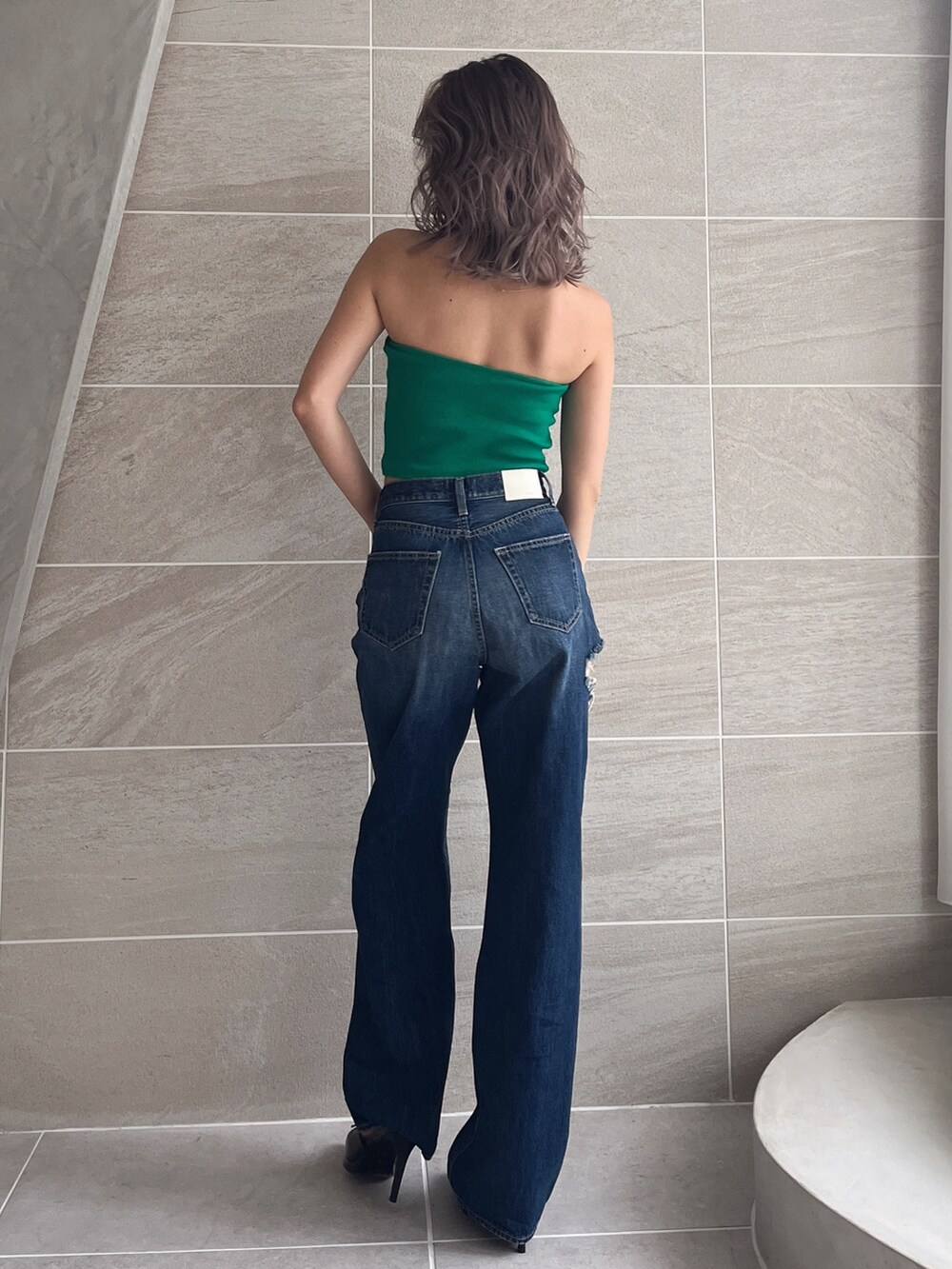 ブルー系のデニムパンツ、グリーン系のチューブトップを着用したレディースの春コーディネートの2枚目の写真