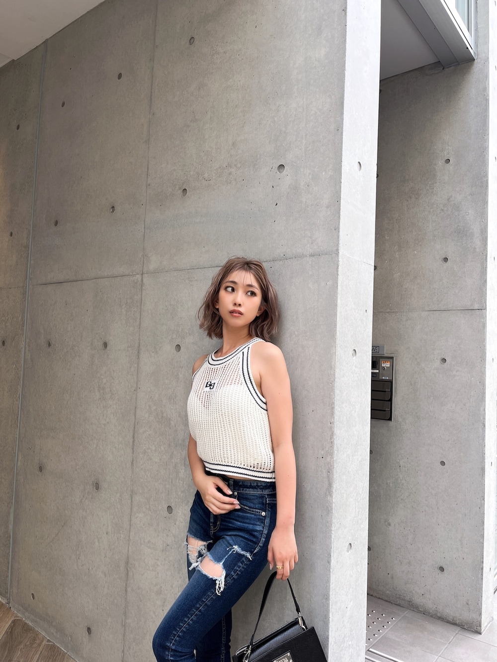 ホワイト系のニット/セーター、ブルー系のデニムパンツ、ブラック系のサンダルを着用したレディースの夏コーディネートの4枚目の写真