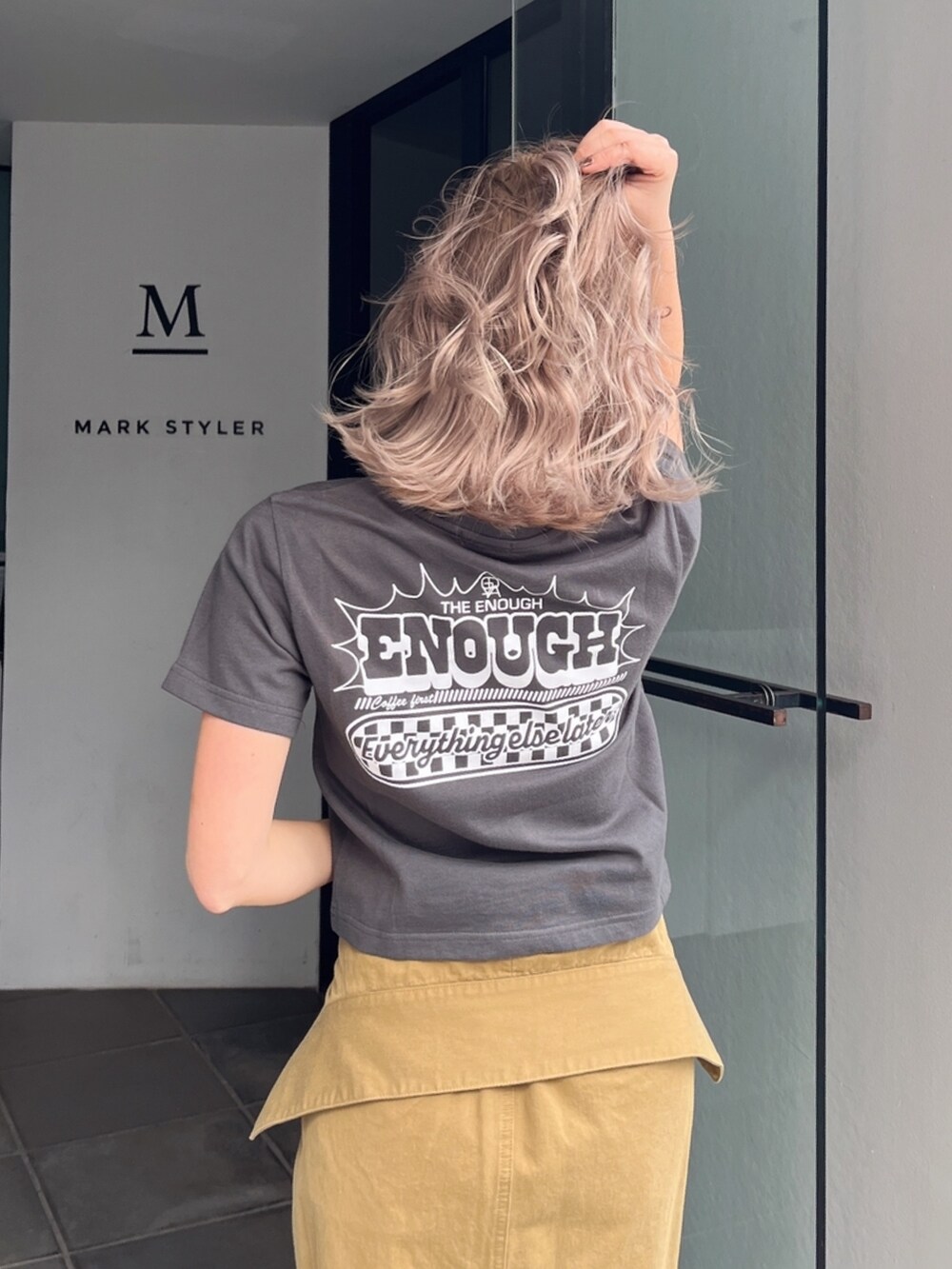 グレー系のTシャツ/カットソー、グリーン系のスカート、ブラック系のサンダルを着用したレディースの秋コーディネートの7枚目の写真