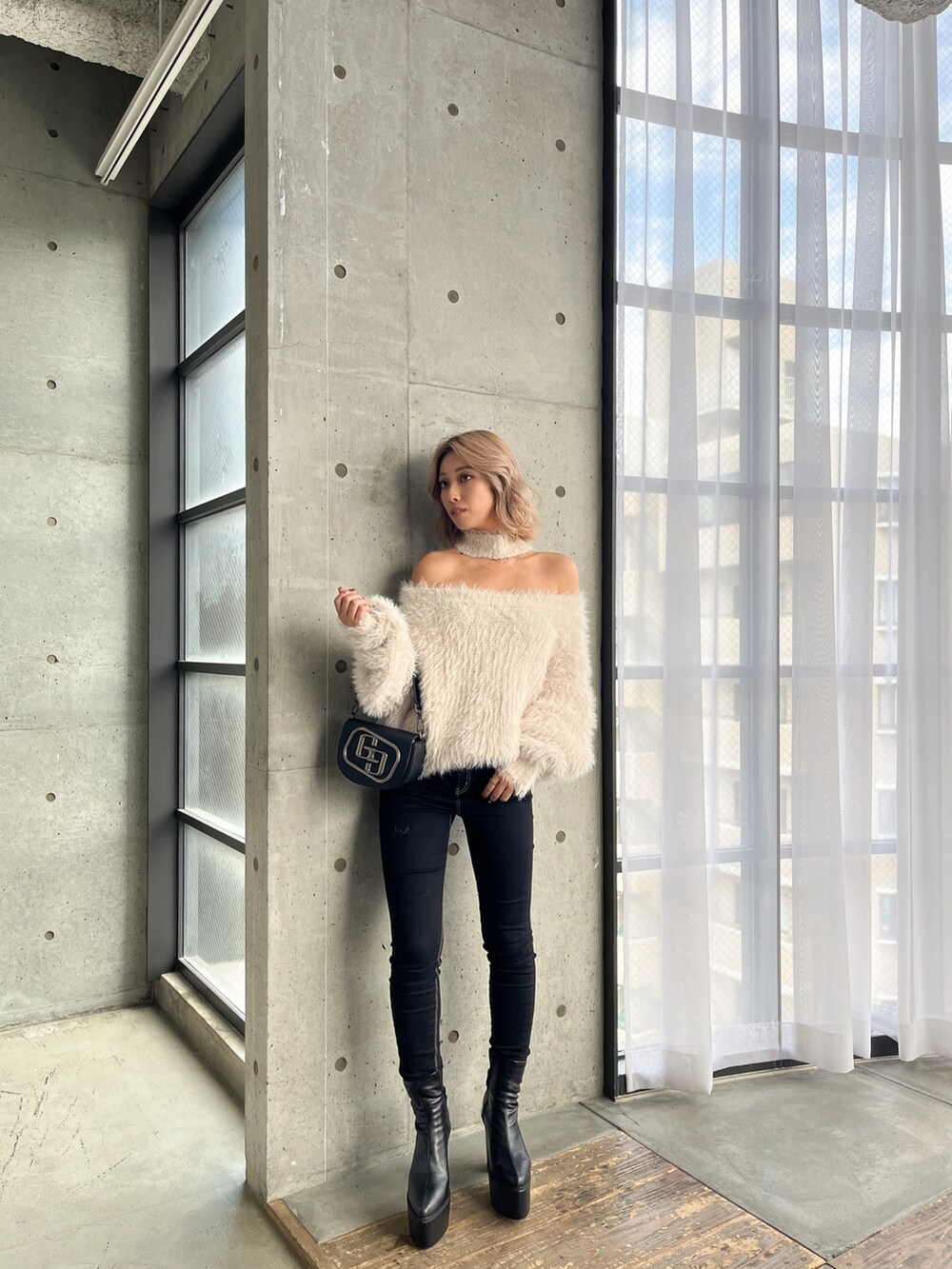 ホワイト系のニット/セーター、ブラック系のデニムパンツ、ブラック系のブーツを着用したレディースの秋コーディネートの3枚目の写真