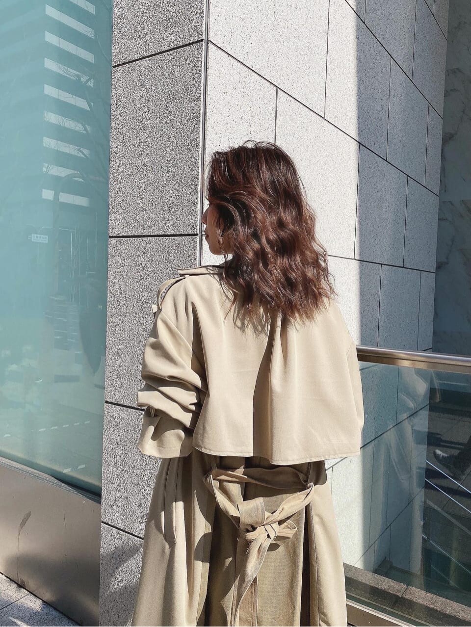 ベージュ系のトレンチコート、ホワイト系のデニムパンツ、ホワイト系のニット/セーターを着用したレディースの春コーディネートの3枚目の写真