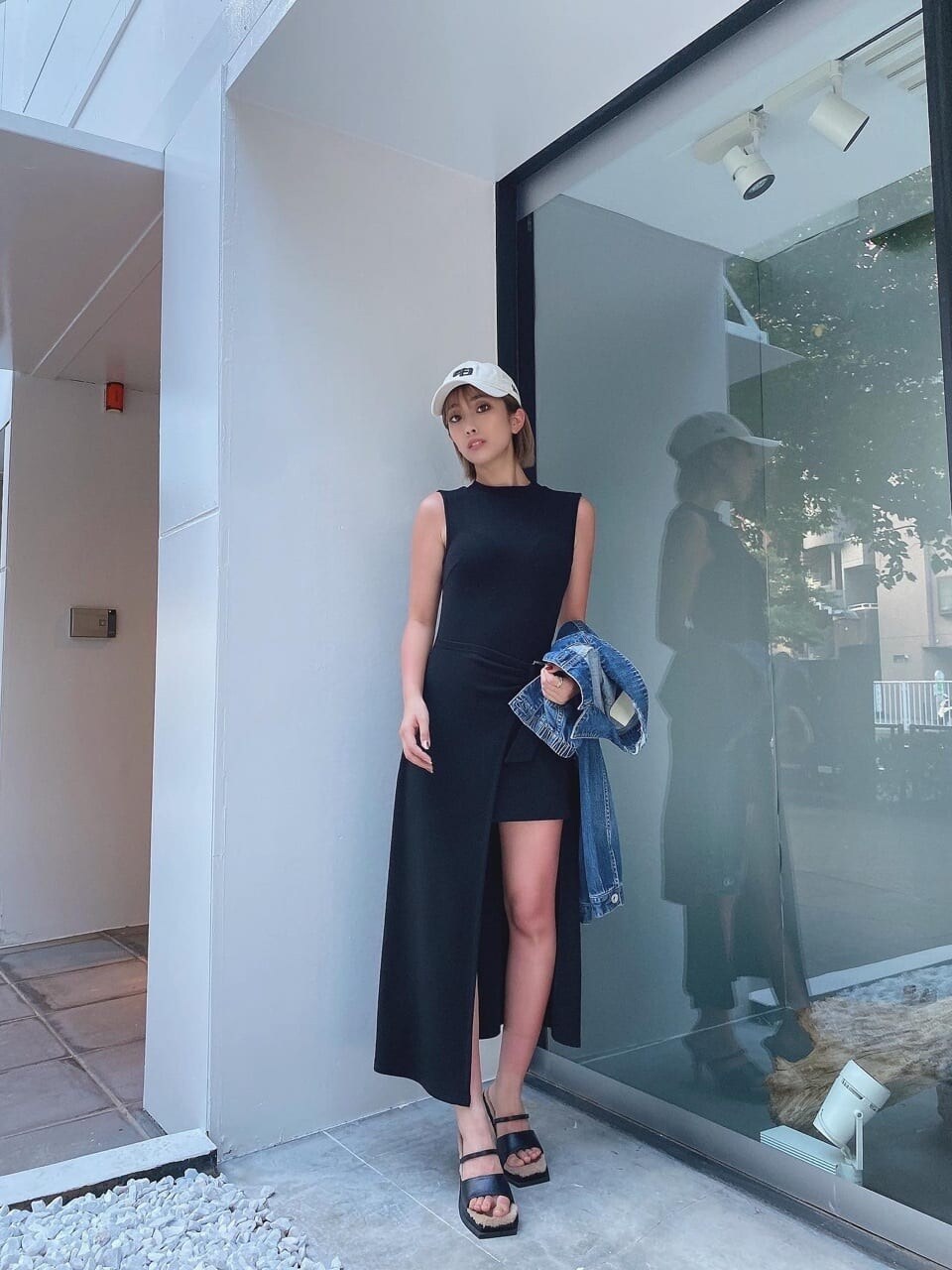 ブラック系のワンピース、ブラック系のサンダル、ホワイト系のキャップを着用したレディースの夏コーディネートの3枚目の写真