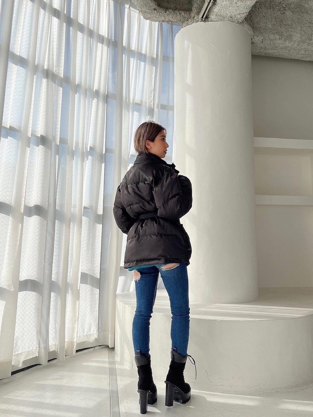 ブラック系のMA-1、ブルー系のデニムパンツ、ブラック系のブーツを着用したレディースの秋コーディネートの4枚目の写真