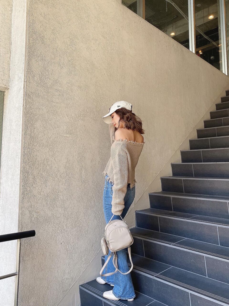 ブルー系のデニムパンツ、ベージュ系のニット/セーター、ホワイト系のキャップを着用したレディースの冬コーディネートの2枚目の写真