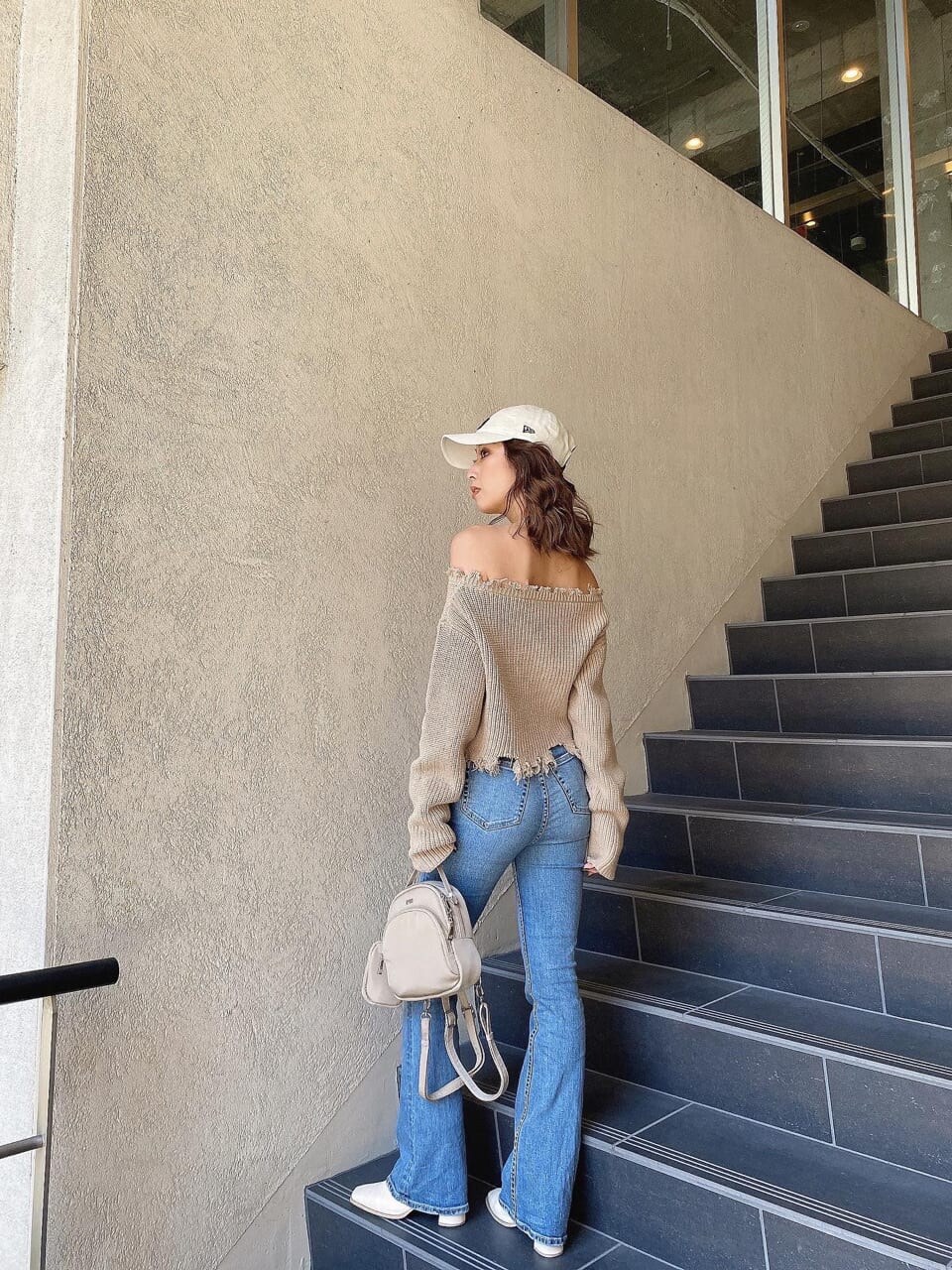 ブルー系のデニムパンツ、ベージュ系のニット/セーター、ホワイト系のキャップを着用したレディースの冬コーディネートの3枚目の写真