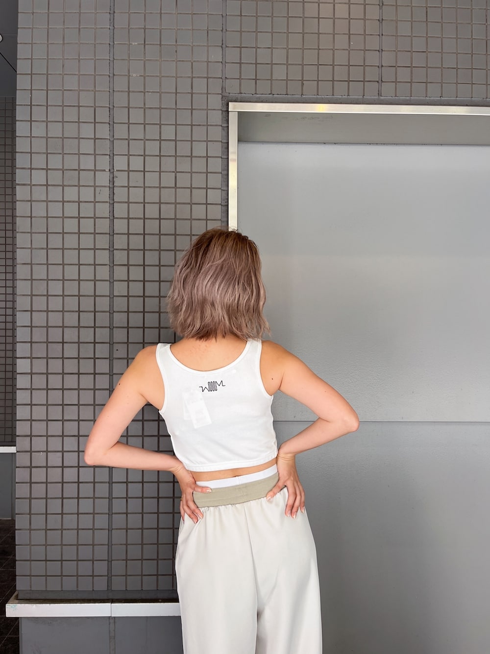 ホワイト系のタンクトップ、ホワイト系のスウェットパンツ、ホワイト系のパンプスを着用したレディースの夏コーディネートの4枚目の写真
