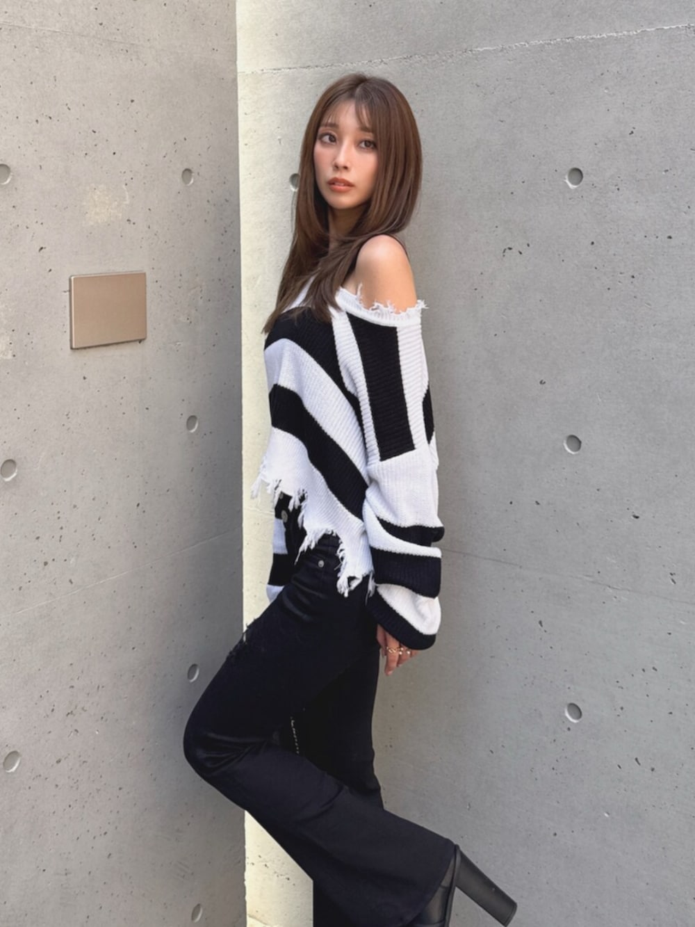 ブラック系のデニムパンツ、ブラック系のブーツ、ホワイト系のハンドバッグを着用したレディースの秋コーディネートの7枚目の写真