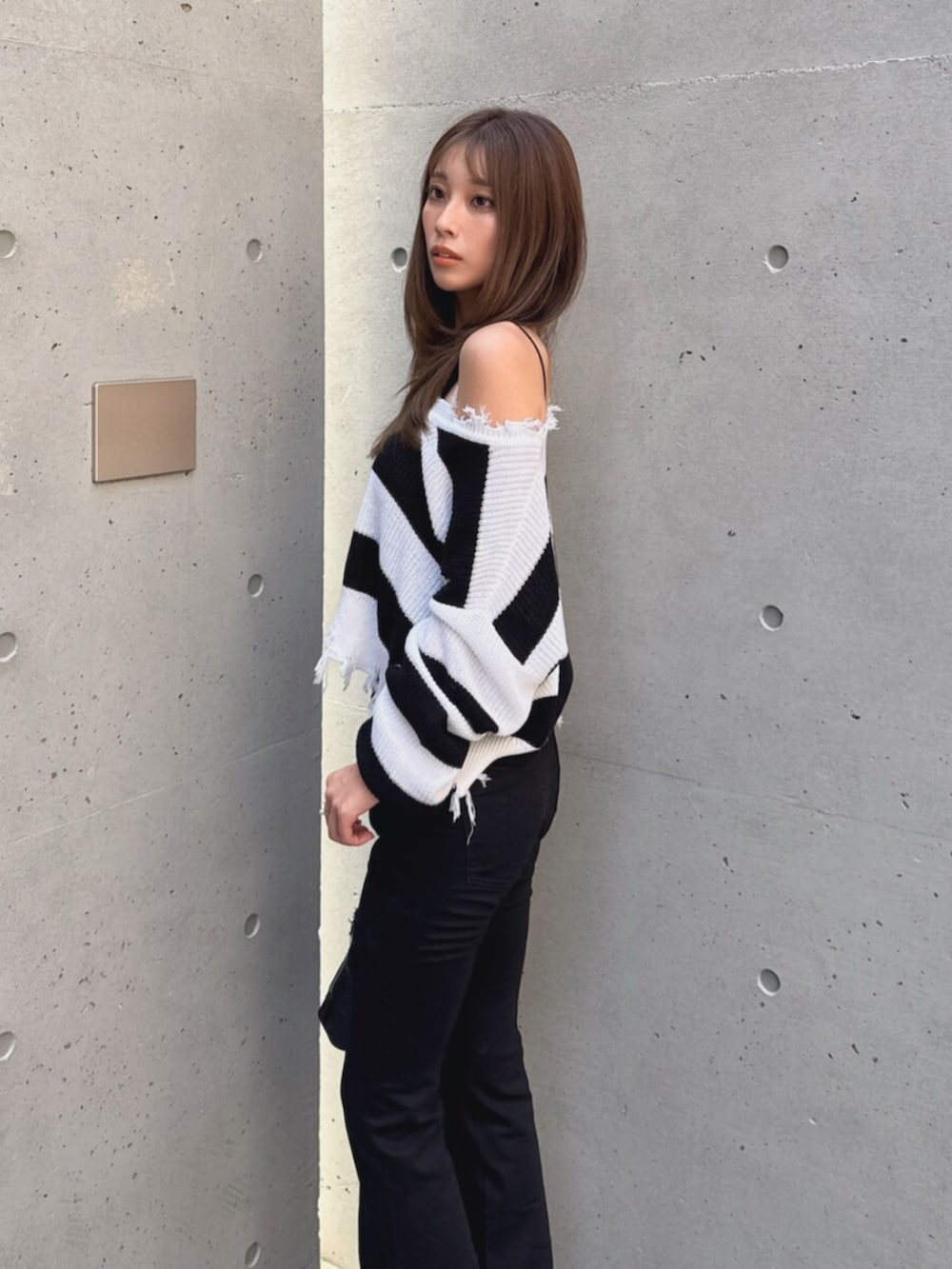 ブラック系のデニムパンツ、ブラック系のブーツ、ホワイト系のハンドバッグを着用したレディースの秋コーディネートの6枚目の写真