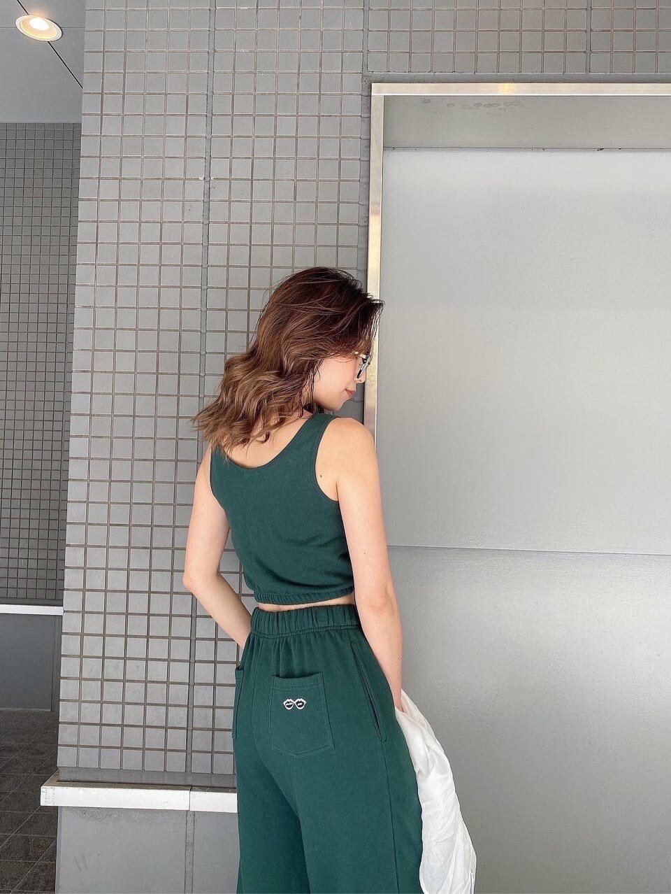 ホワイト系のパンプス、グリーン系のスウェットパンツ、グリーン系のキャミソールを着用したレディースの春コーディネートの6枚目の写真