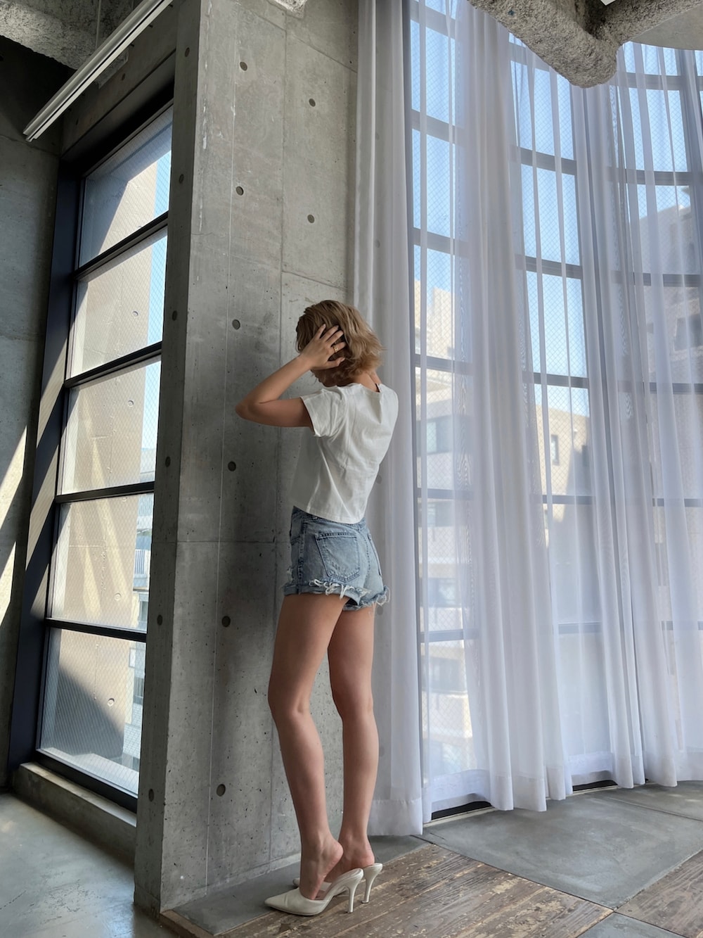 ブルー系のデニムパンツ、ホワイト系のTシャツ/カットソー、ホワイト系のパンプスを着用したレディースの春コーディネートの3枚目の写真