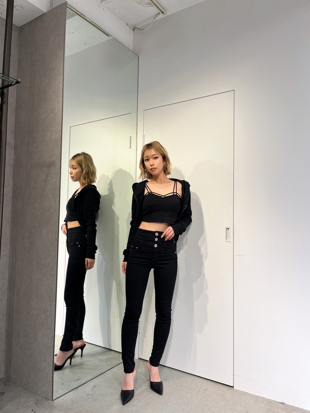 ブラック系のデニムパンツ、ブラック系のパーカー、ブラック系のキャミソールを着用したレディースの春コーディネートの4枚目の写真