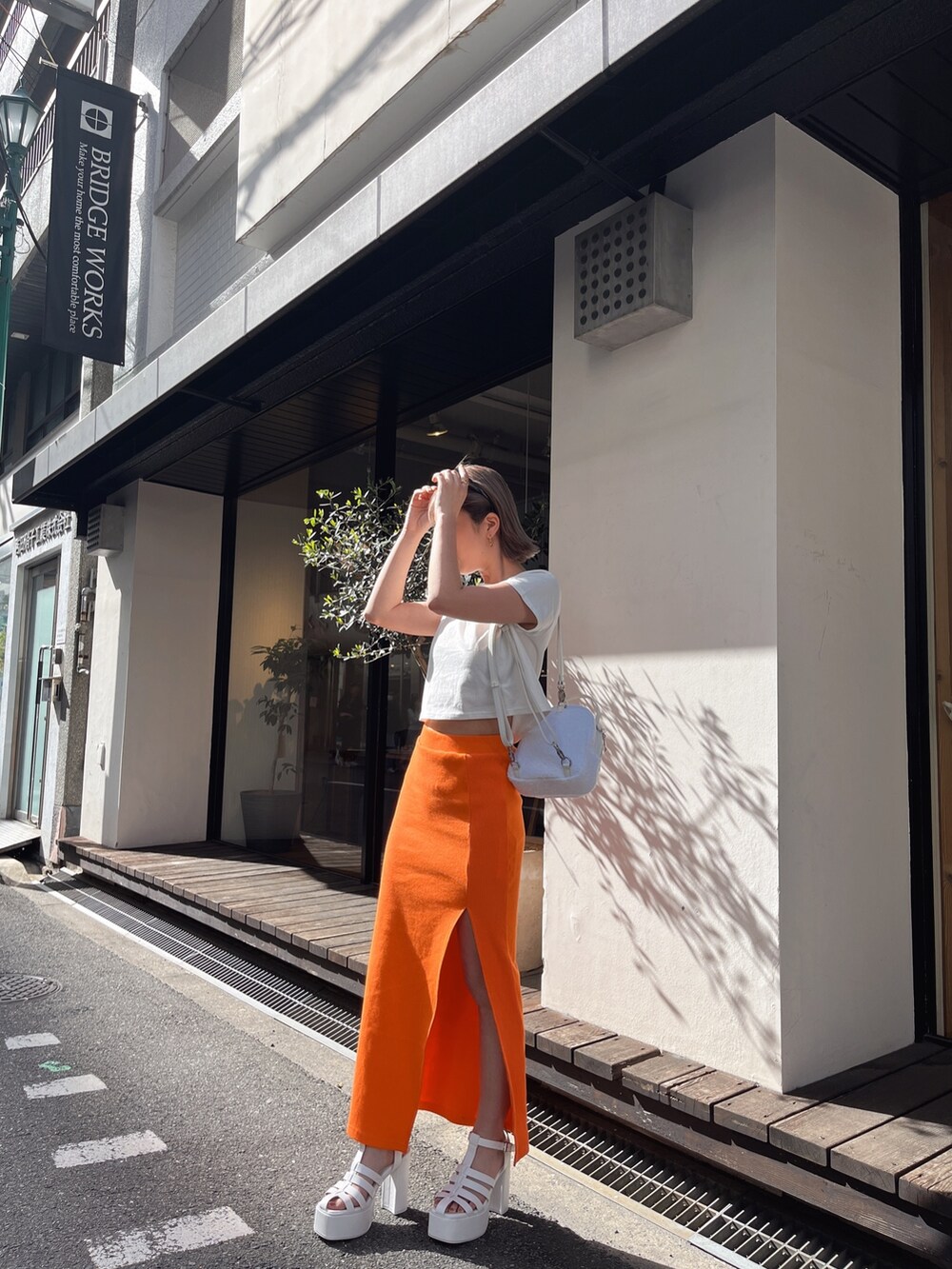 ホワイト系のTシャツ/カットソー、オレンジ系のスカートを着用したレディースの春コーディネートの5枚目の写真