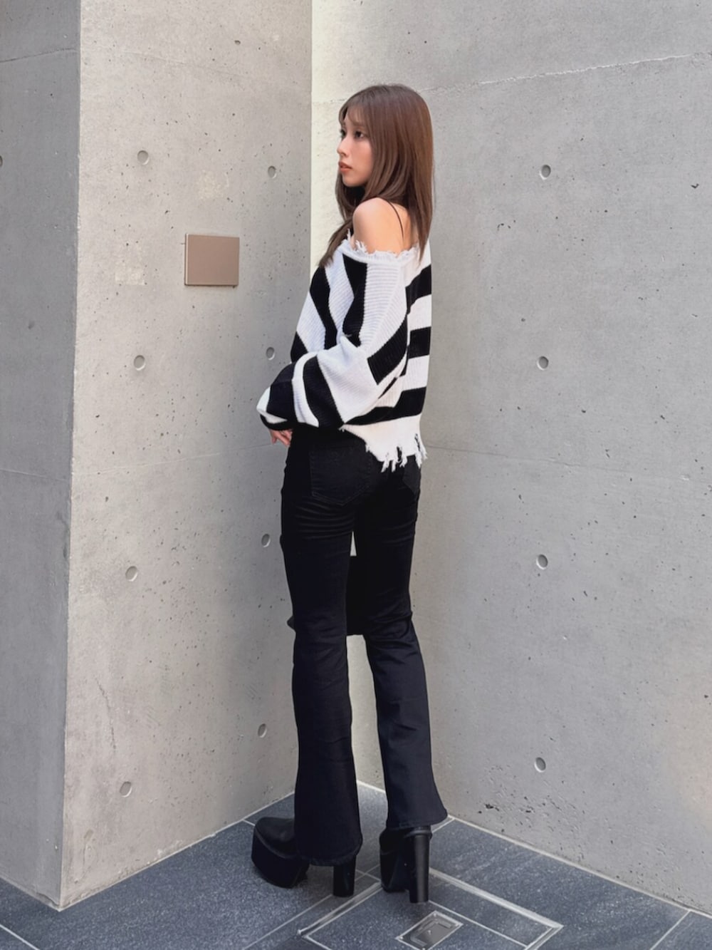 ブラック系のデニムパンツ、ブラック系のブーツ、ホワイト系のハンドバッグを着用したレディースの秋コーディネートの4枚目の写真