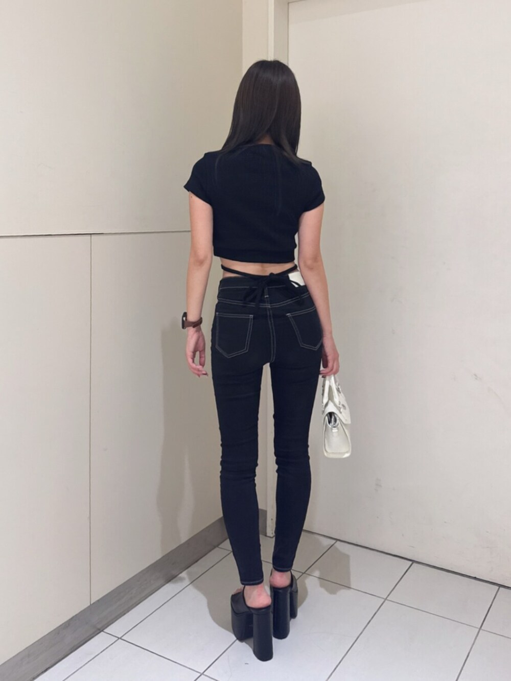 ブラック系のサンダル、ブラック系のハンドバッグ、ブラック系のデニムパンツを着用したレディースの夏コーディネートの3枚目の写真
