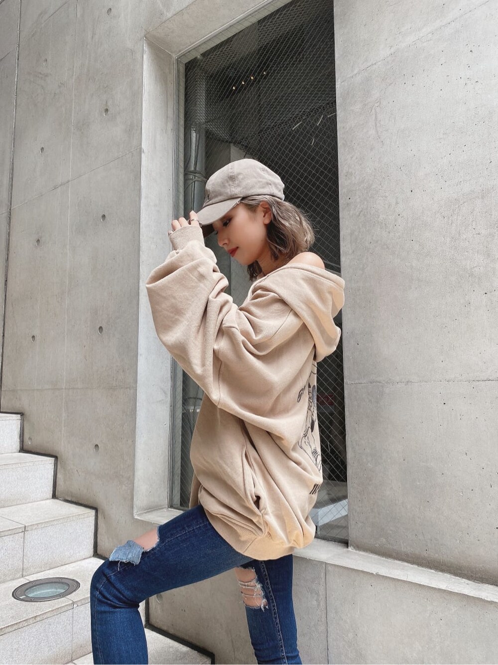 ブルー系のデニムパンツ、ベージュ系のパーカー、ベージュ系のキャップを着用したレディースの秋コーディネートの3枚目の写真