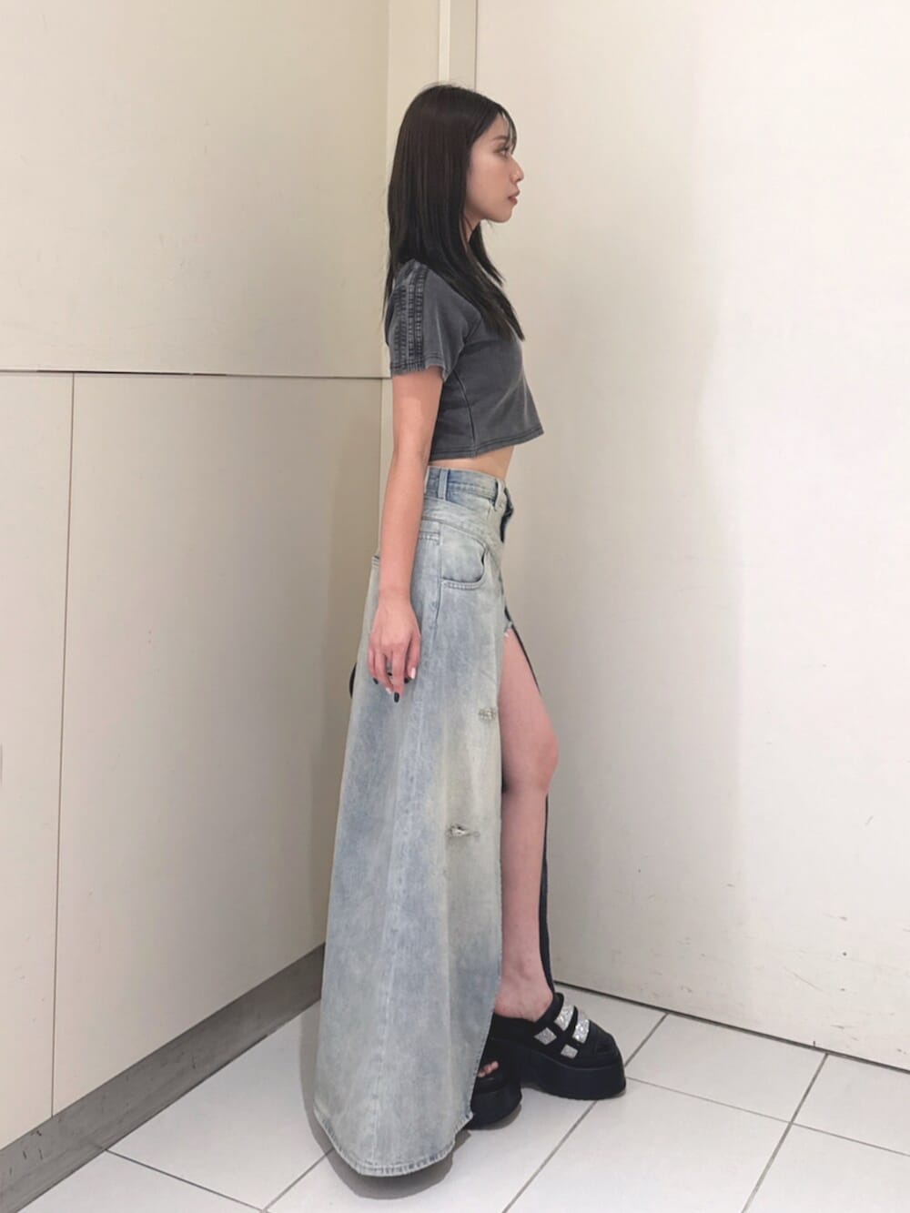 ブラック系のハンドバッグ、ブルー系のデニムスカート、ブラック系のサンダルを着用したレディースの夏コーディネートの2枚目の写真