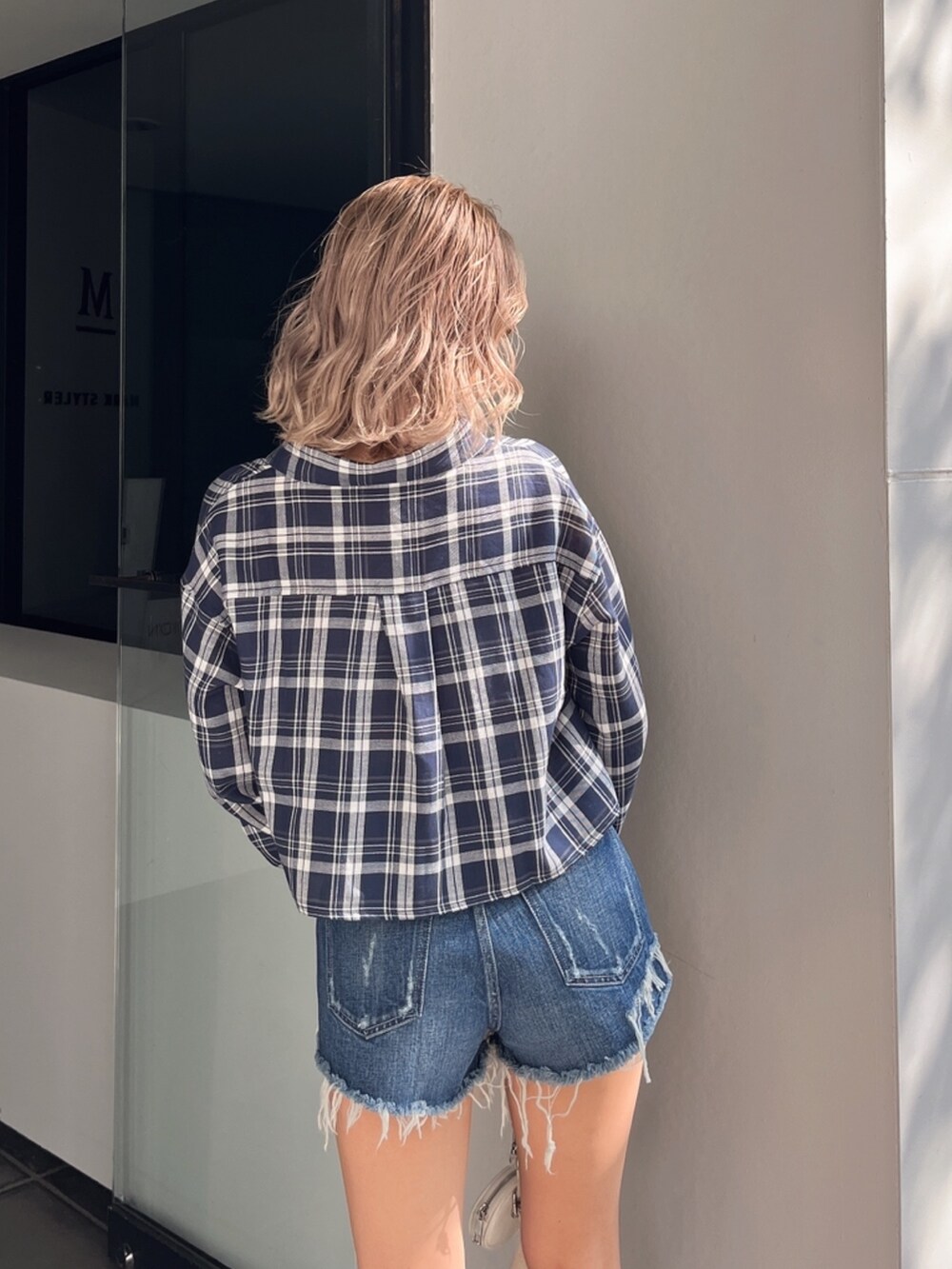 ブルー系のシャツ/ブラウス、ブラック系のハンドバッグ、ブラウン系のサングラスを着用したレディースの春コーディネートの4枚目の写真