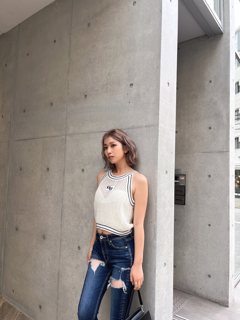 ホワイト系のニット/セーター、ブルー系のデニムパンツ、ブラック系のサンダルを着用したレディースの夏コーディネートの3枚目の写真