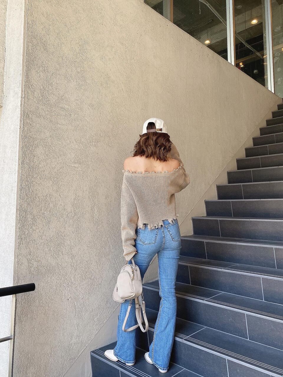 ブルー系のデニムパンツ、ベージュ系のニット/セーター、ホワイト系のキャップを着用したレディースの冬コーディネートの4枚目の写真