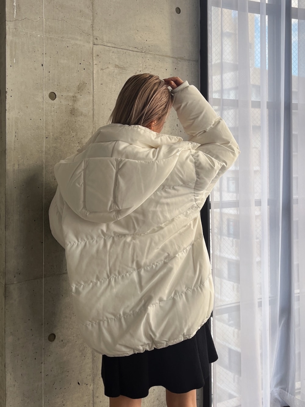 ブラック系のワンピース、ブラック系のブーツ、ホワイト系のダウンジャケット/コートを着用したレディースの冬コーディネートの4枚目の写真