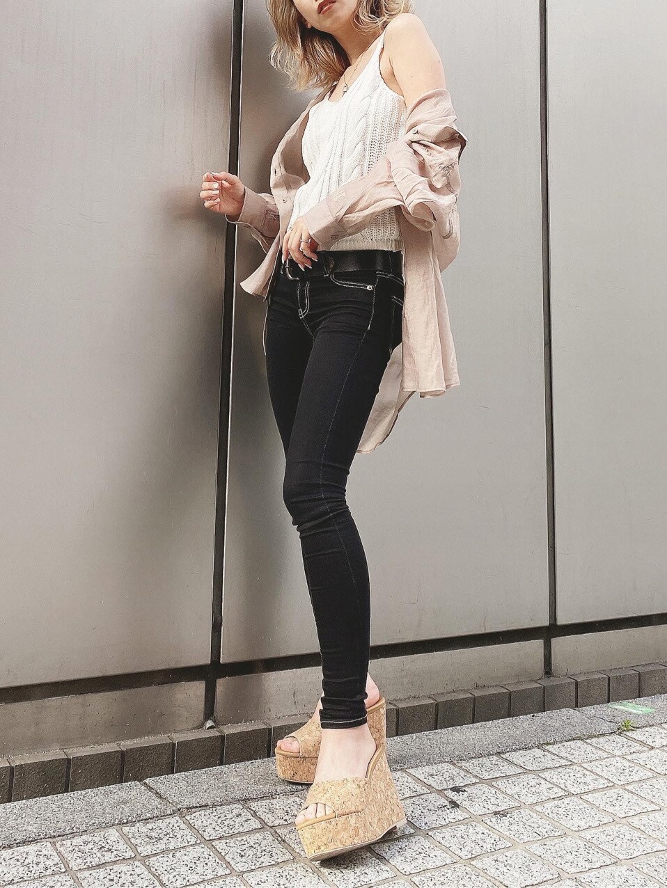 ホワイト系のキャミソール、ブラック系のデニムパンツ、ブラウン系のサンダルを着用したレディースの春コーディネートの2枚目の写真