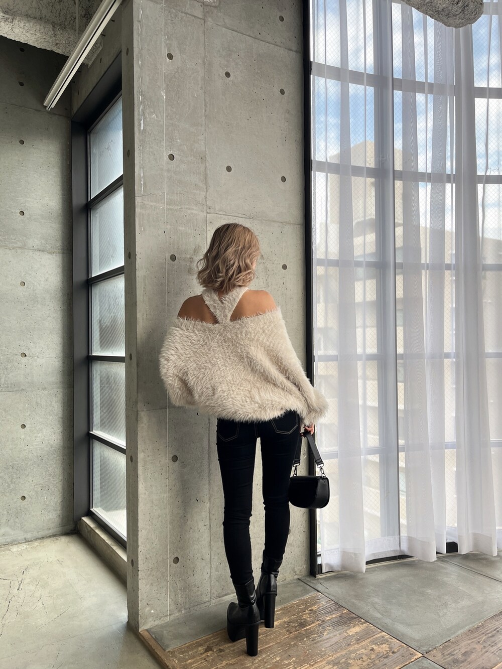 ホワイト系のニット/セーター、ブラック系のデニムパンツ、ブラック系のブーツを着用したレディースの秋コーディネートの4枚目の写真