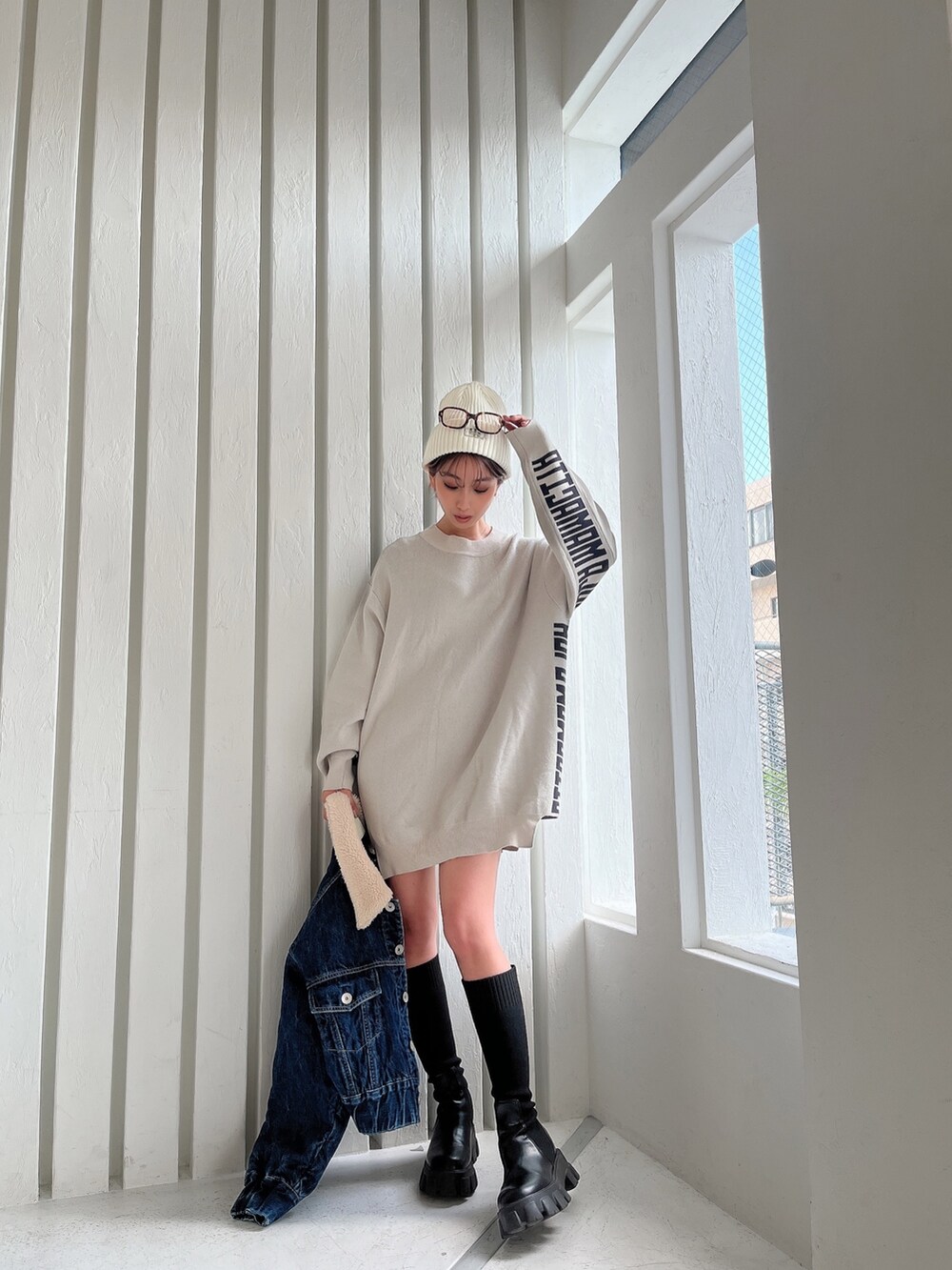 ホワイト系のニット/セーター、ブルー系のデニムジャケット、ブラック系のブーツを着用したレディースの秋コーディネートの5枚目の写真