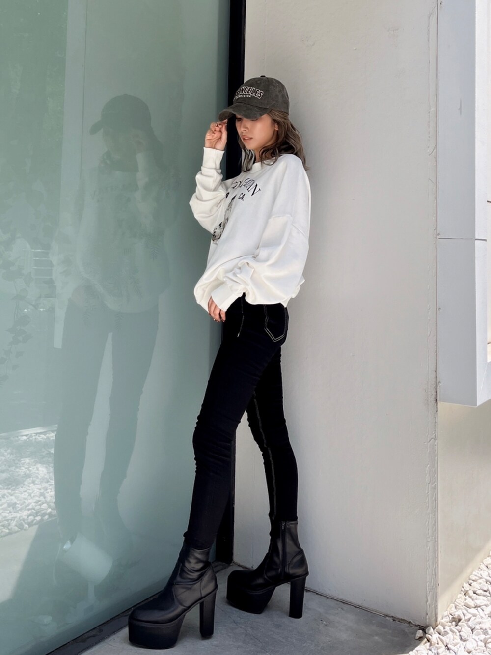 ホワイト系のスウェット、ブラック系のデニムパンツ、ホワイト系のブーツを着用したレディースの冬コーディネートの2枚目の写真