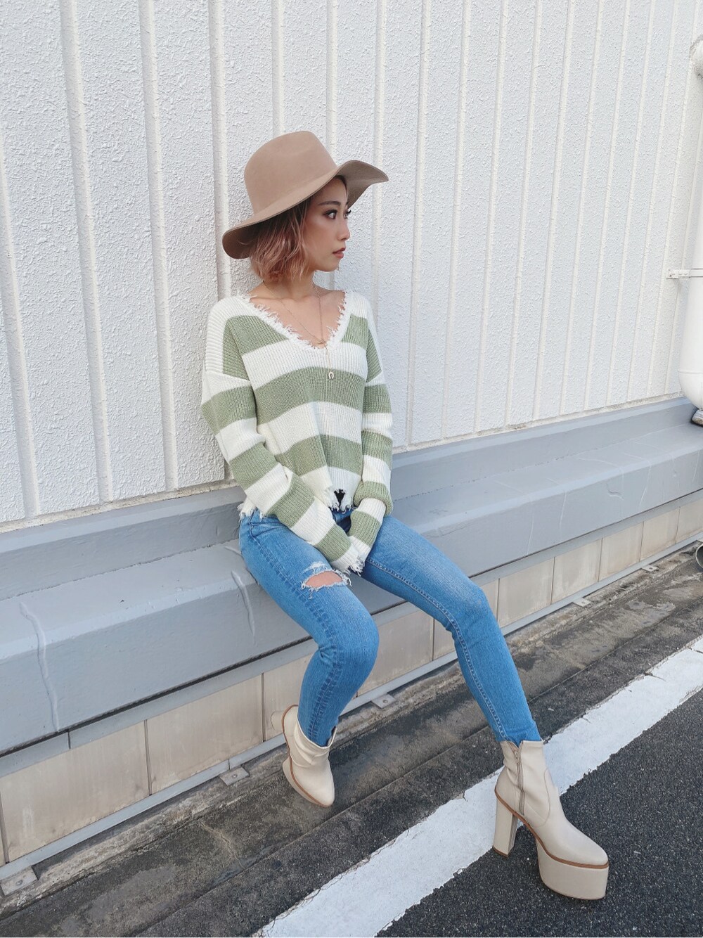 ブルー系のデニムパンツ、グリーン系のニット/セーター、ホワイト系のブーツを着用したレディースの冬コーディネートの3枚目の写真