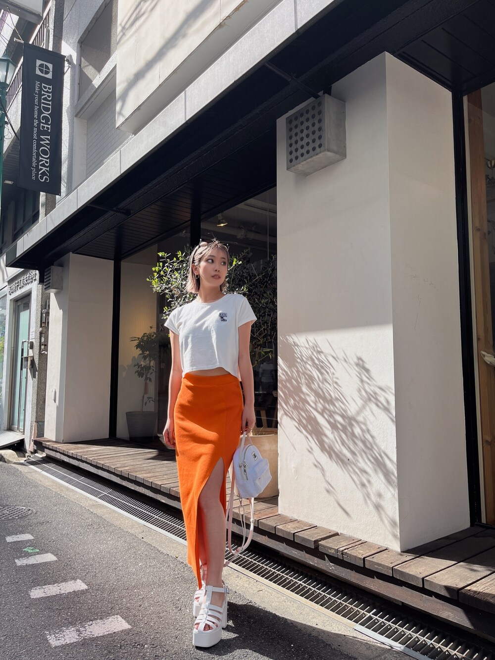 ホワイト系のTシャツ/カットソー、オレンジ系のスカートを着用したレディースの春コーディネートの3枚目の写真