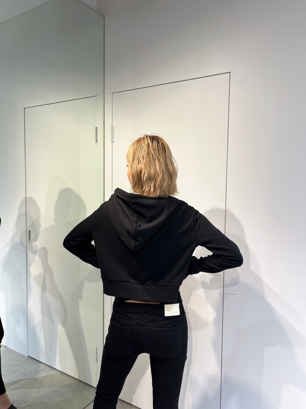 ブラック系のデニムパンツ、ブラック系のパーカー、ブラック系のキャミソールを着用したレディースの春コーディネートの7枚目の写真