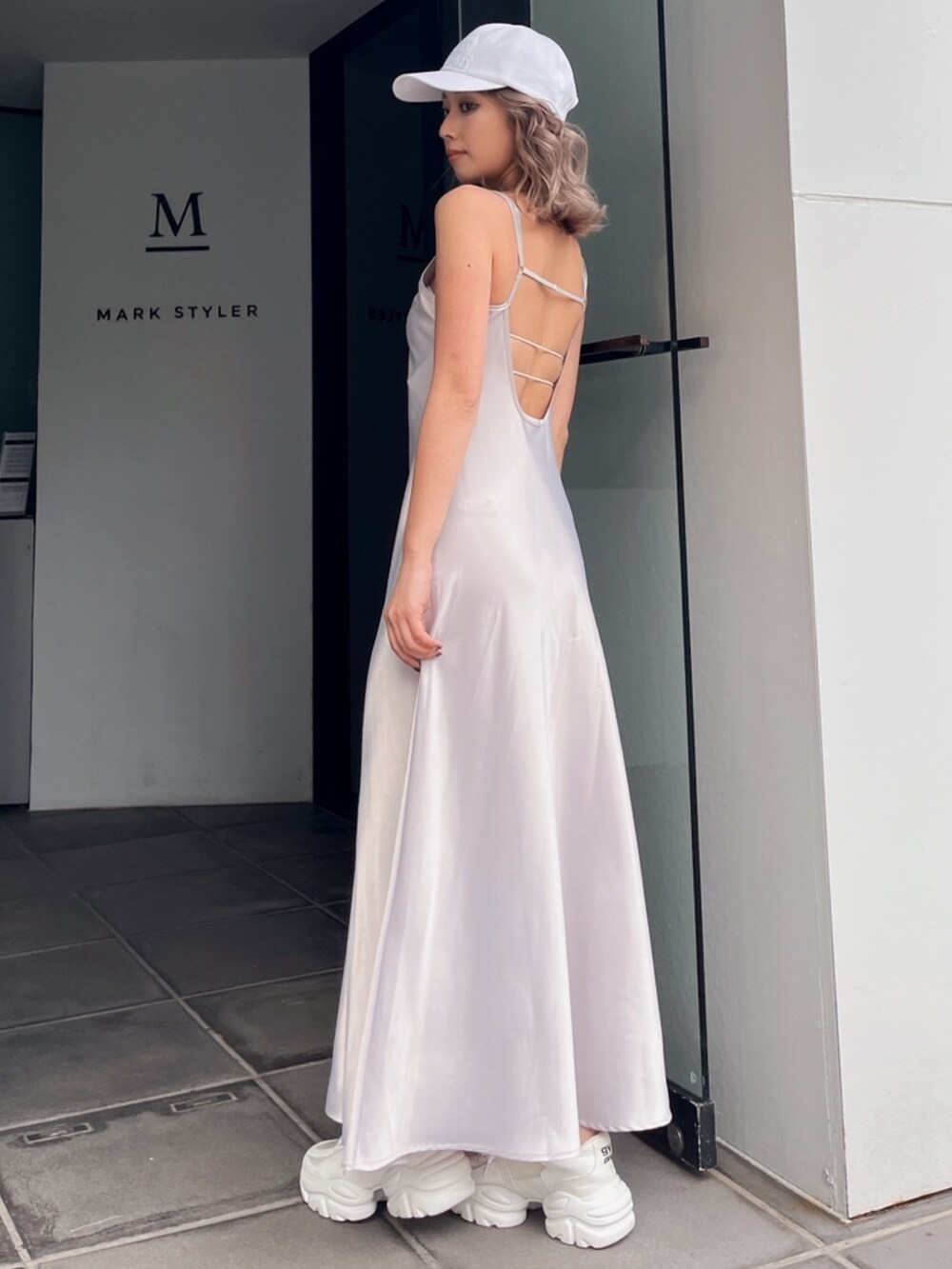 グレー系のワンピース、ホワイト系のキャップを着用したレディースの夏コーディネートの2枚目の写真