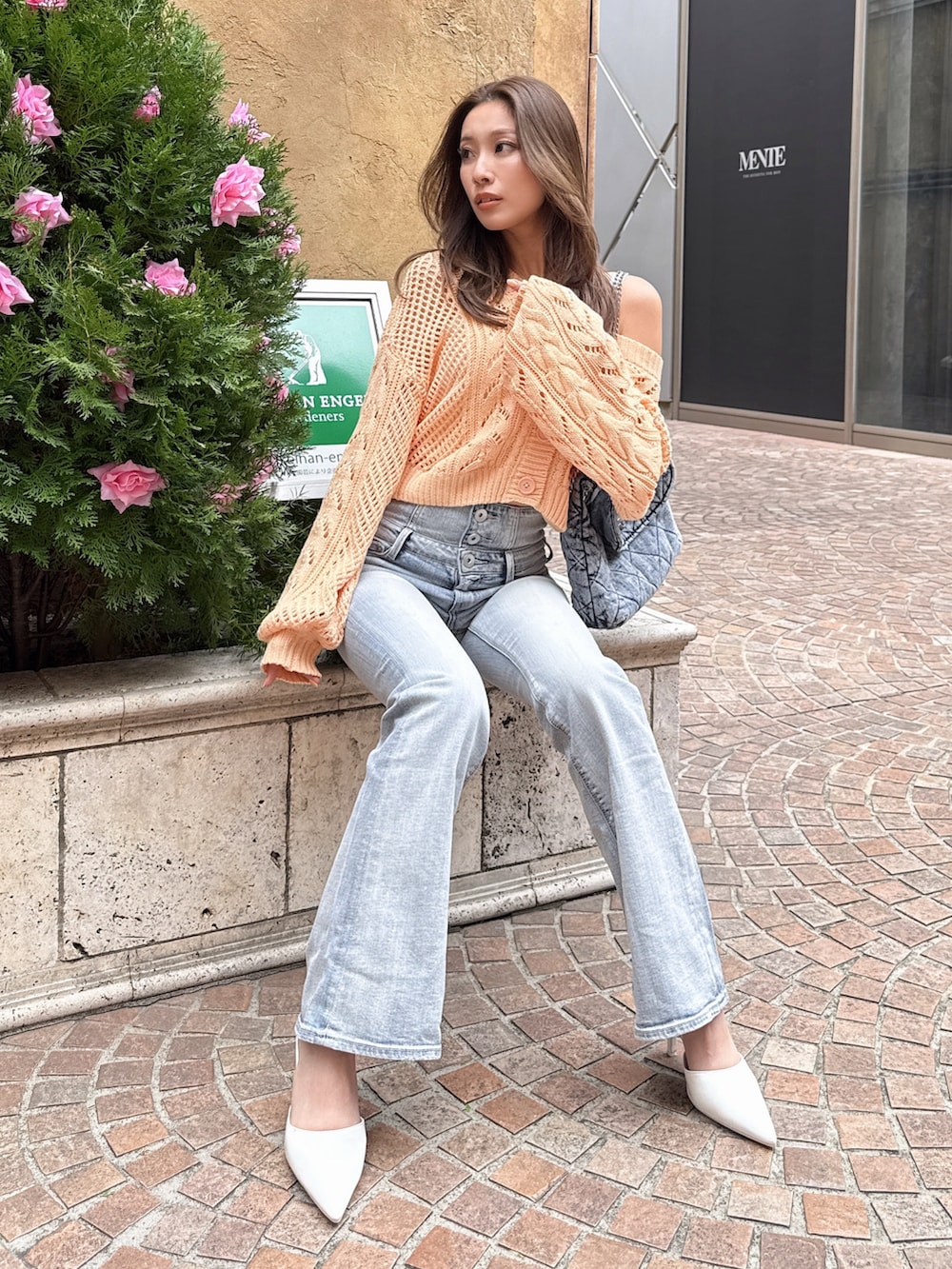 オレンジ系のニット/セーター、ブルー系のデニムパンツを着用したレディースの春コーディネートの2枚目の写真